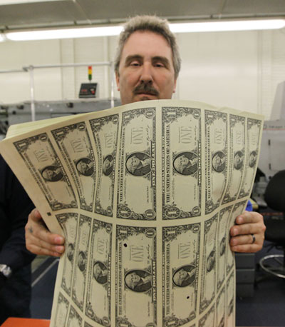 Man holding newly printed cash.